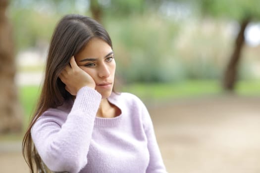 Bored woman sitting in a park alone