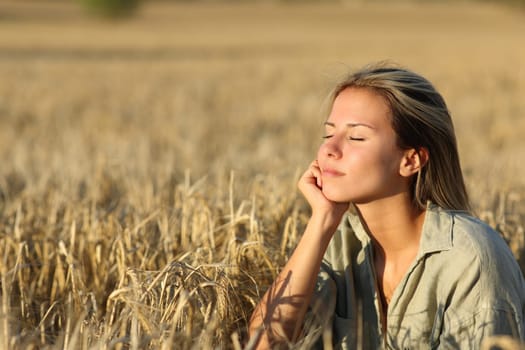 Relaxed woman in a field at sunset resting