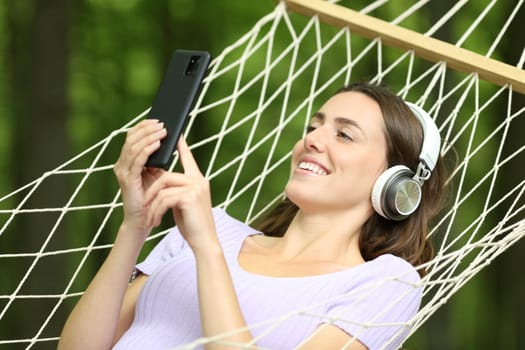 Happy woman on hammock listening music in a green forest