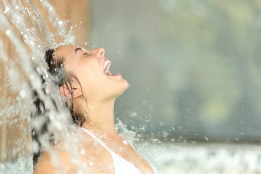Happy woman screaming under water jet in spa