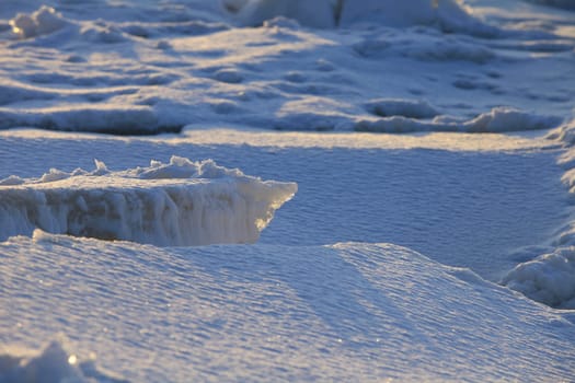 ice hummocks are covered with snow, illuminated by the rays of the winter sun