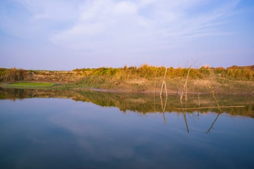 Canal with green grass and vegetation reflected in the water nearby Padma river in Bangladesh