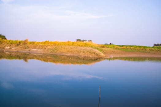 Canal with green grass and vegetation reflected in the water nearby Padma river in Bangladesh