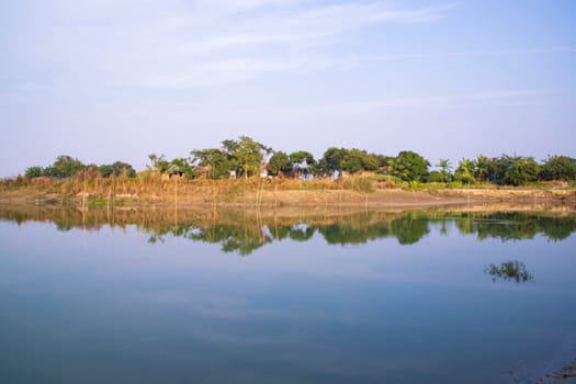 Canal with trees and vegetation reflected in the water nearby Padma river in Bangladesh
