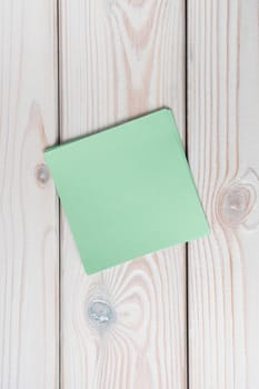 Flat lay of empty blank green sticker sticky note on grey wooden table. Note, paper, reminder, information, announcement, memory, message, bookmark, brainstorming. Top view, copy space, vertical.