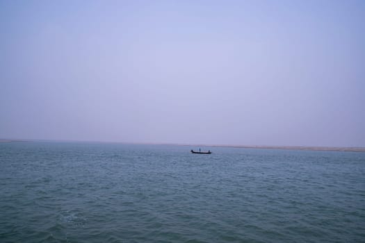 landscape view of Padma river on a fishing boat with a sand island under the blue sky