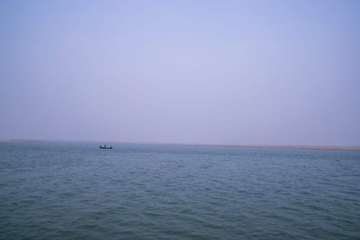 landscape view of Padma river on a fishing boat with a sand island under the blue sky