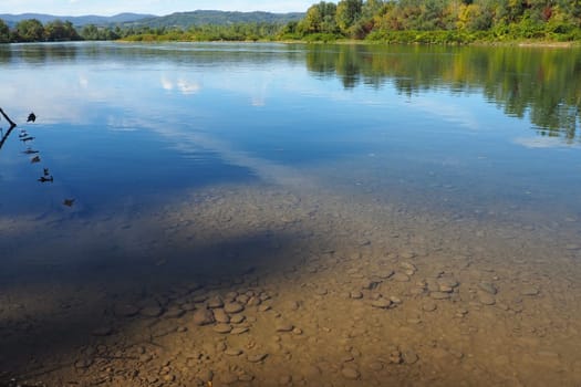 Drina river near the town of Banja Koviljaca, Serbia, view of the coast of Bosnia and Herzegovina. Rybnik on the Drina. The flow of water, blue sky, greenery on the opposite side of the river