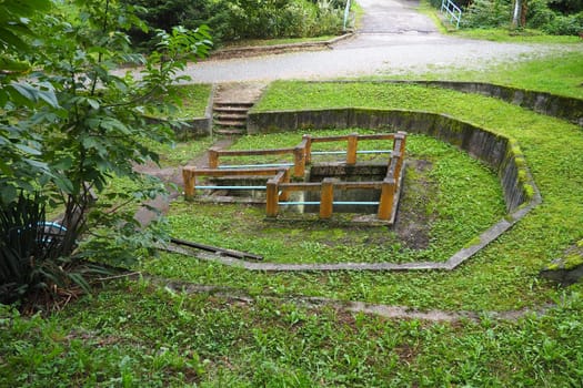 Banja Koviljaca, Loznica, Serbia. Mount Guchevo, park and forest. Source of mineral sulfuric and ferruginous water Rakina Chesma Cesma. A spring near the road to Guchevo. Concrete fence and stairs