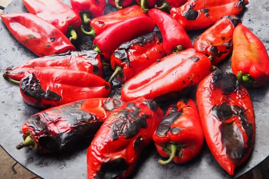 Roasting delicious red peppers for a smoky flavor and quick peeling. Balkan salad recipes. Thermal processing of the pepper crop on a metal circle. Peppers are laid out on a flat baking sheet close-up