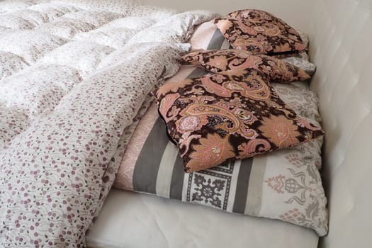 Pink decorative pillows on the bed linen. Double bridal bed with pillows and thick feather duvet. Bedroom design. Soft white headboard. Interior with furniture and bedding