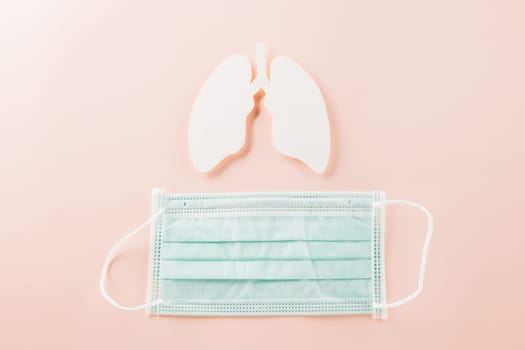 World Tuberculosis Day. Overhead lungs paper symbol and facial medical face mask on pink background, lung cancer awareness, copy space concept of world TB day, banner background, pneumonia awareness
