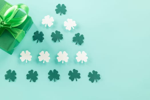 Happy St Patrick's Day decoration background concept. Top view gift box green clover leaves, shamrocks leaves holiday symbol with copy space on blue background
