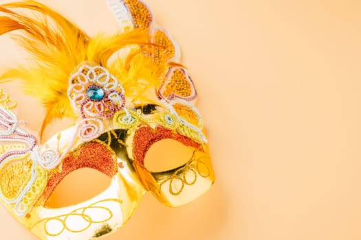 Happy Purim carnival decoration. Golden venetian ball mask isolated on pastel background, Jewish Purim and Mardi Gras in Hebrew, holiday background banner design with copy space, Masquerade party