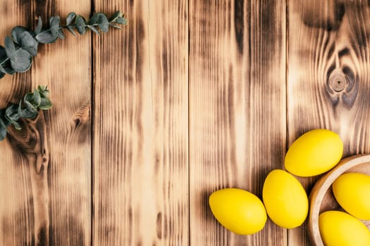 Easter composition of greeting celebration postcard for holiday with wooden background and yellow colored chicken eggs. Decoration for home. Copy space. Celebration of event, traditional holiday