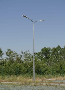 one street pole with two lanterns in nature in the summer day