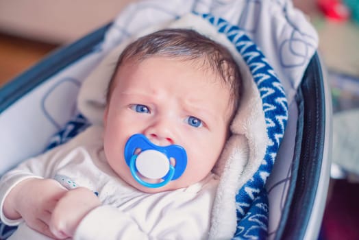 Close portrait of a white newborn baby with a pacifier in his mouth