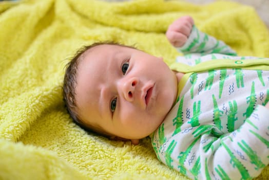 Beautiful newborn white baby lies on a yellow blanket