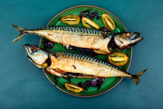 Whole tasty mackerel fish grilled with kiwi on a plate