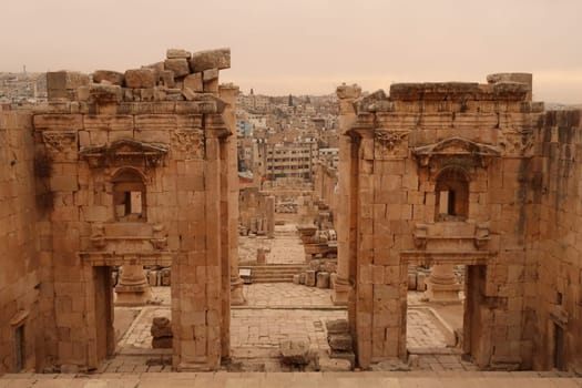 Entrance gate to the Temple of Artemis, Propylaeum of the Sanctuary of Artemis with the modern city of Jerash in the background, Gerasa, Jordan 2021