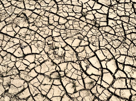 Deep cracks in the land as a symbol of hot climate and drought. Desert and cracked ground. Uneven, swollen ground. Emptiness and death. Ecological and natural theme