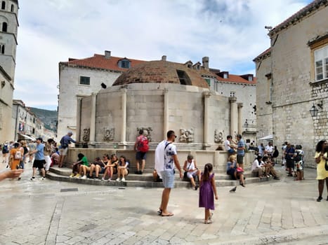 Big Onofrio Fountain, Velika Onofrijeva chesma, Dubrovnik, Croatia. Water supply established during the Quattrocento period. Numerous multinational happy tourists walk on the Stradun 14 August 2022.