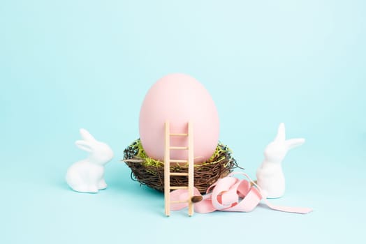 Easter bunny or rabbit sitting next to a huge pink colored egg in a birds nest, gift ribbon and ladder, spring holiday