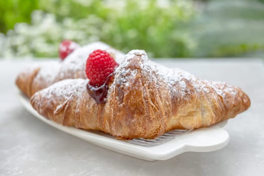 Croissants with jam and berries for Breakfast. Behind, a defocus background.