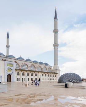 Istanbul, Turkey - August 31 2022: Side shot of Grand Camlia Mosque, or Buyuk Camlica Camii, with few pedestrians, a modern complex for Islamic worship, built in 2019, located in Camlica hill, Uskudar