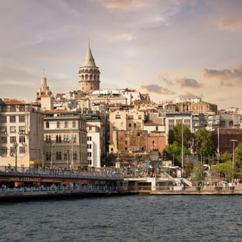 Istanbul, Turkey - August 25, 2022: City skyline including Galata Bridge with traditional fish restaurants in the passage under the bridge, and Galata Tower in the far end