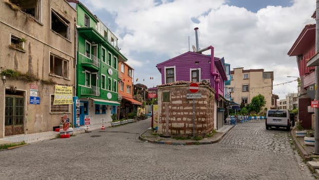 Istanbul, Turkey - August 30, 2022: Cobblestone alley, with beautiful old colorful traditional houses, painted in green, orange and pink, suited in Kapiagasi Street, Fatih district, in a summer day