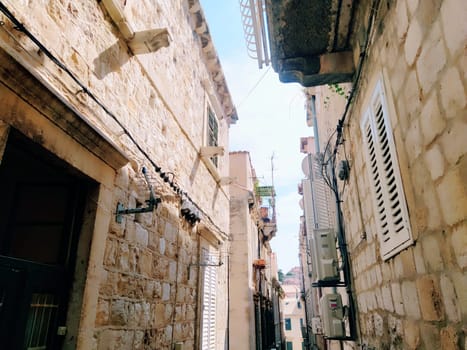 Dubrovnik, Croatia, 08.14. 2022. Narrow streets of the ancient town. The facades of the houses are made of marble and stone very close to each other. Windows with shutters. Summer tourism in Adriatic