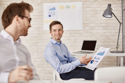 Successful businessman explaining charts to colleague in office