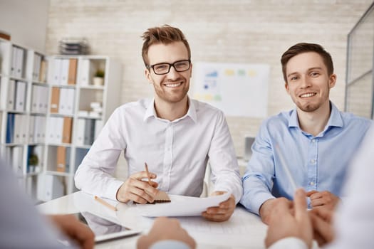 Two successful businessmen looking at camera at workplace in office