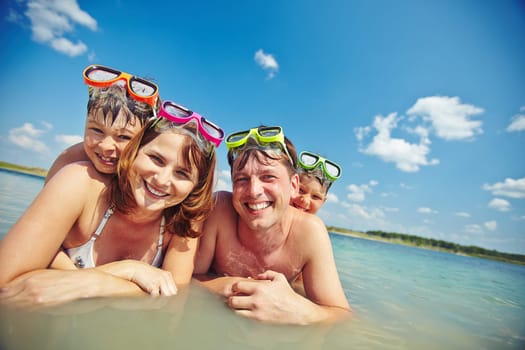 Happy family in goggles looking at camera in water