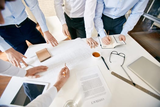 Group of architects with pencils discussing sketch at workplace