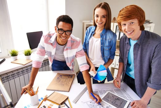 Happy designers looking at camera by their workplace