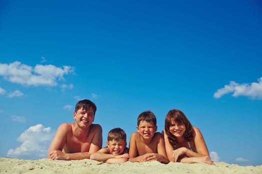 Happy family of four sunbathing on hot summer day