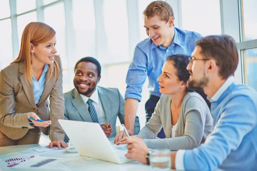 Group of employees looking at confident manager explaining her ideas at meeting