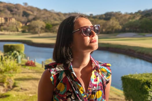 Young woman in sunglasses enjoying summer breeze at the beach. Closeup