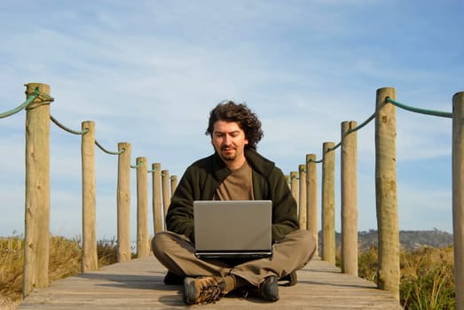 young man working with computer at the beach