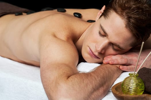 Young man getting a stone massage at spa