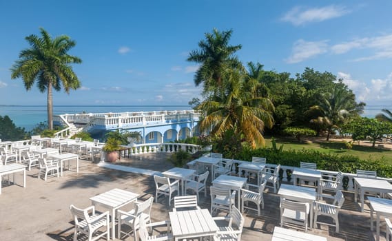 White tables and chairs  in tropical garden  on a beautiful  beach of Jamaica