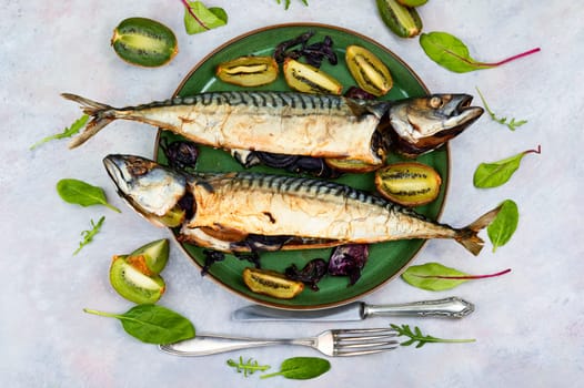 Two appetizing mackerel fish baked with kiwi pieces. Top view