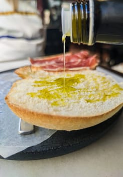 Pouring olive oil over freshly made toast slice. Selective focus