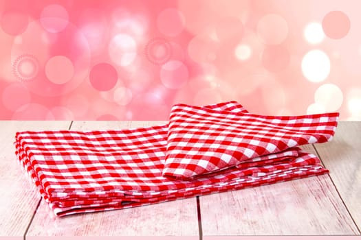 Empty wooden bright desk table with red checkered tablecloth over abstract blurred bright background. Template for your food and product display montage.