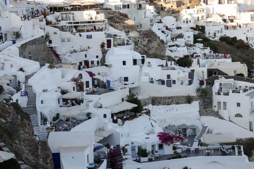 Oia, Santorini, Greece - June 28, 2021: Whitewashed houses with terraces and pools and a beautiful view in Oia on Santorini island, Greece