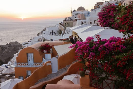 Oia, Santorini, Greece - June 28, 2021: Whitewashed houses and windmills in Oia in warm rays of sunset on Santorini island. Greece