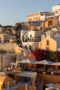 Oia, Santorini, Greece - June 28, 2021: Whitewashed houses and windmills in Oia in warm rays of sunset on Santorini island. Greece