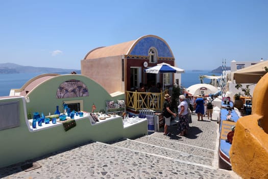 Oia, Santorini, Greece - July 3, 2021: Tourists while walking through the narrow streets of Oia, Santorini, Greece